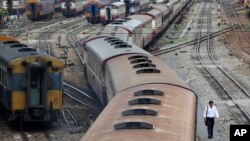 FILE - In this photo taken July 10, 2014, a man walks along rail tracks in Bangkok. Thailand's military government has approved a massive budget to upgrade the country's railways including high-speed rails that would eventually link with China. 