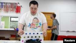 John Cronin, seorang penderita Down Syndrome dan salah satu pendiri John’s Crazy Socks, sebuah toko kaus kaki online yang mendonasikan persentase dari hasil penjualannya ke lembaga-lembaga amal yang membantu penyandang disabilitas, tampak sedang membungkus pesanan kaus kaki di kantor pusat perusahaan tersebut di Melville, New York, AS, 23 Juli 2018 (foto: REUTERS/Shannon Stapleton) 
