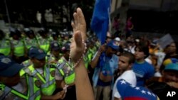 Seorang demonstran mengangkat tangannya yang memegang rosario, dalam protes menentang pemerintah di Caracas, Venezuela (23/1). (AP/Fernando Llano)