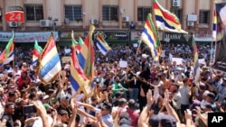 In this photo released by Suwayda24, people stage a protest as they wave the Druze flags in the southern city of Sweida, Syria, Sept. 1, 2023. The protests in the Druze-majority city have been ongoing for nearly two weeks.