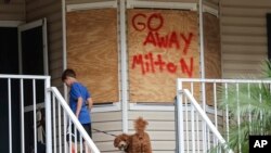 Noah Weibel and his dog Cookie climb the steps to their home as their family prepares for Hurricane Milton, in New Port Richey, Florida, Oct. 7, 2024.