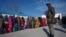 Voters line up to cast their votes as an Indian security officer stands guard outside a polling station during the last phase of the Jammu and Kashmir state assembly elections on the outskirts of Jammu, Dec. 20, 2014.