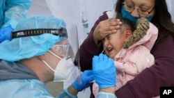 10일 미국 유타주 솔트레이크시티의 신종 코로나바이러스 감염 임시 검사소에서 주방위군 요원이 어린이로부터 검체를 채취하고 있다.