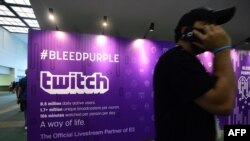 FILE - A man on his cellphone walks past an advertising board for Twitch, the official Livestream Partner of E3, during the 2016 Electronic Entertainment Expo (E3) annual video game conference and show in Los Angeles, California, June 14, 2016. 