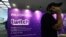 FILE - A man on his cellphone walks past an advertising board for Twitch, the official Livestream Partner of E3, during the 2016 Electronic Entertainment Expo (E3) annual video game conference and show in Los Angeles, California, June 14, 2016. 