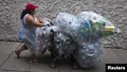 Seorang perempuan berjalan di sepanjang 41st Street dengan tas berisi botol dan kaleng untuk didaur ulang di wilayah Manhattan di New York, 30 September 2015. (REUTERS / Carlo Allegri)