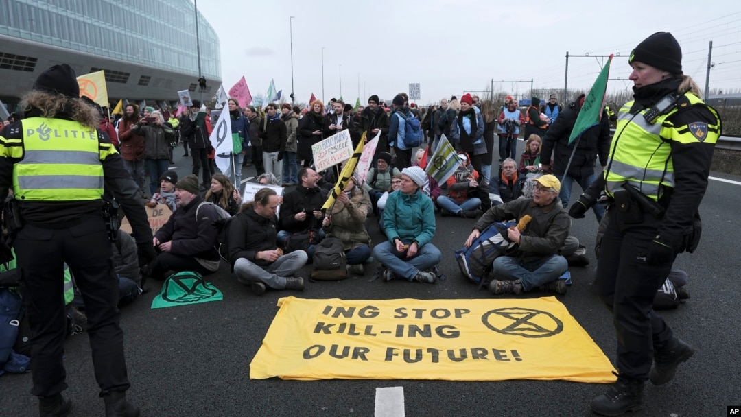 Police talk with climate activists blocking the main highway around Amsterdam near the former headquarters of ING bank on Dec. 30, 2023. They were protesting the financing of fossil fuels.