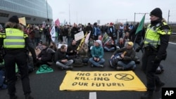 Police talk with climate activists blocking the main highway around Amsterdam near the former headquarters of ING bank on Dec. 30, 2023. They were protesting the financing of fossil fuels.