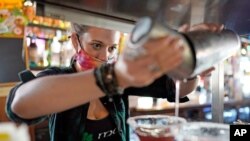 Bartender Alyssa Dooley makes a cocktail at Mo's Irish Pub, March 2, 2021, in Houston. Texas Gov. Greg Abbott announced that he is lifting business capacity limits and the state's mask mandate starting next week.