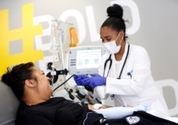 FILE - Phlebotomist Jenee Wilson talks with Melissa Cruz, an ER technician for Valley Medical Center who has recovered from COVID-19, as she finishes donating convalescent plasma in Seattle, April 17, 2020.