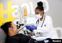FILE - Phlebotomist Jenee Wilson talks with Melissa Cruz, an ER technician for Valley Medical Center who has recovered from COVID-19, as she finishes donating convalescent plasma in Seattle, April 17, 2020.