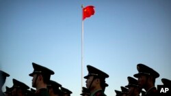 FILE - Chinese paramilitary police stand in formation after a flag raising ceremony at Tiananmen Square on National Day. Methods of torture outlined by Amnesty include beatings, sleep deprivation, being forced into painful positions for long periods, and 