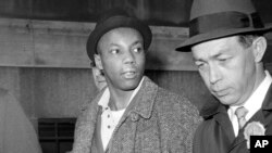 FILE - Norman 3X Butler, 26, a suspect in the slaying of Malcolm X, is escorted by detectives at police headquarters, after his arrest, in New York, Feb. 26, 1965. 