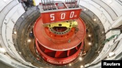 FILE - Employees take part in the installation of a turbine rotary wheel, which weighs 244 tons and was earlier transported from a plant in St. Petersburg, inside the hydro unit number 9 at Krasnoyarsk hydroelectric power station on the Yenisei River outside Krasnoyarsk, Russia, Nov. 17, 2017. 