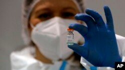 FILE - In this Tuesday, Jan. 19, 2021 file photo, a medical worker poses with a vial of the Sinopharm's COVID-19 vaccine in Belgrade, Serbia. 