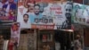 A police officer sits below a billboard showing a portrait of Baba Siddique, a senior politician, at the spot where Siddique was shot at outside his son's office in Mumbai, Oct. 13, 2024. 