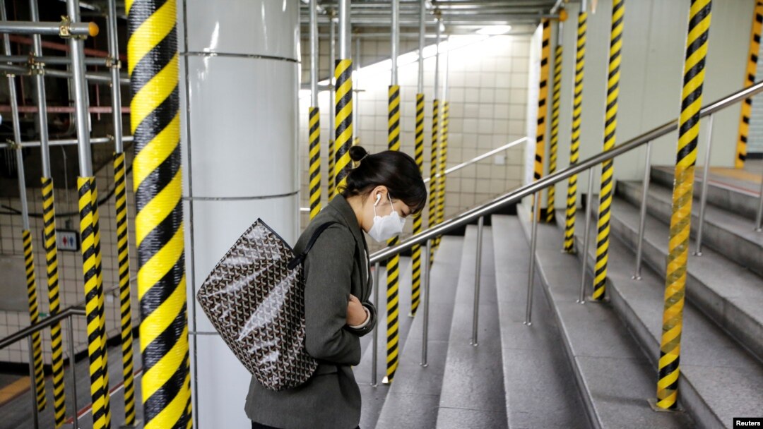 Seorang warga mengenakan masker saat menaiki tangga di stasiun kereta api di Seoul, Korea Selatan, 20 Februari 2020. 