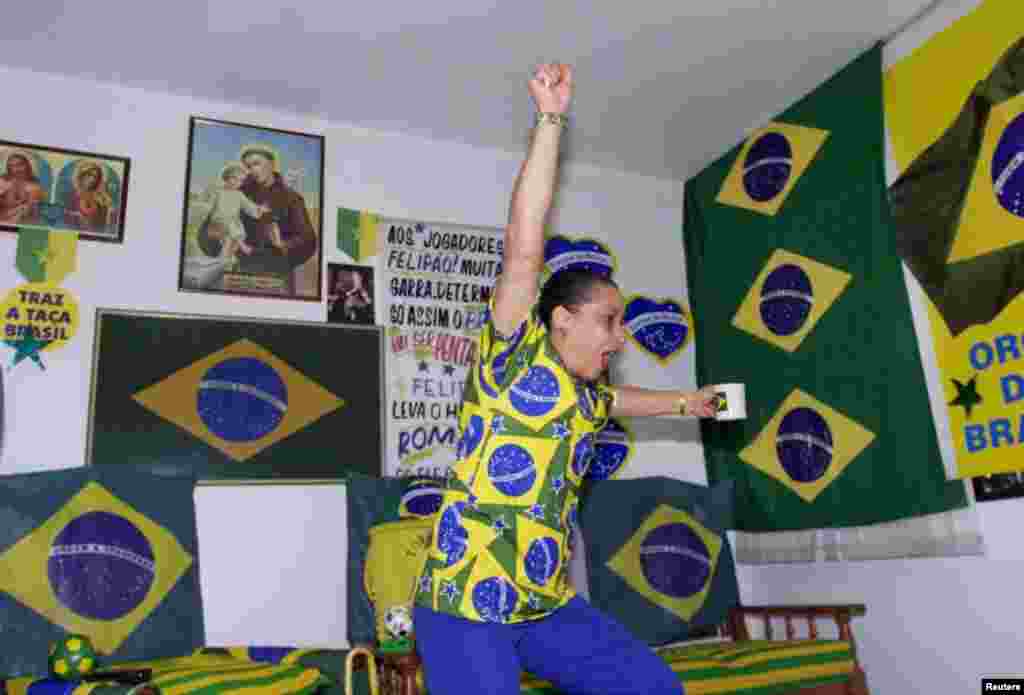 Vestida com as cores nacionais e segurando a sua chávena de café, Marilza Guimaraes da Silva festeja na sua o golo de Ronaldo contra a Turquia, semi-final do Mundial de Futebol, a 26 de Junho de 2002. O Brasil ganhou por 1-0. REUTERS/Jamil Bittar