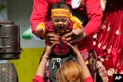 FILE - A young devotee is carried down a truck as they wait for the start of the traditional blessings of replicas of the Black Nazarene outside the Quiapo church in downtown Manila, Philippines, January 4, 2024.