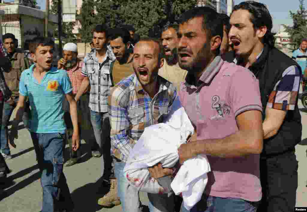 Men react as they carry the body of a relative, whom activists say was killed by barrel bombs dropped by forces loyal to Syria's President Bashar al-Assad in Aleppo's al-Sakhour district, April 30, 2014. 