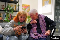 FILE - Holocaust survivor Sarah Jackson, 88, looks at photos from October 7 on a phone with Lala Levi, 27, in Tel Aviv, Israel, January 17, 2024.