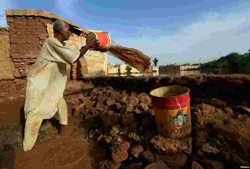 A resident pours out the waters of the Blue Nile floods within the Al-Ikmayr area of Omdurman in Khartoum, Sudan.