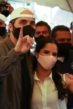 El presidente Nayib Bukele levanta su dedo marcado después de votar, mientras posa con su esposa Gabriela Rodríguez de Bukele en un colegio electoral durante las elecciones locales y legislativas, en San Salvador, el domingo 28 de febrero de 2021.