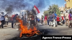 Sudanese protesters walk past burning tires as they rally to protest against the Oct. 2021 military coup, in the capital Khartoum, on Jan. 9, 2022.