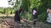 FILE - file photo, July 14, 2017, a woman chops down trees for firewood with her daughter in the small town of Rajaf, near Juba, in South Sudan.