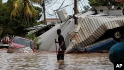 FILE - A resident walking through a flooded street looks back at storm damage caused by Hurricane Eta in Planeta, Honduras, November 6, 2020.