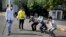 An Indian policeman, left and a civil defense person, second left, make people perform sit ups while holding their ear lobes, as a punishment for stepping out without a valid reason during a lockdown in Ahmedabad, India, Tuesday, March 24, 2020. 