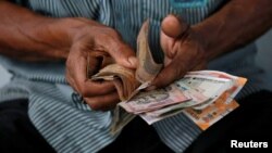 An attendant at a fuel station arranges Indian rupee notes in Kolkata, India, Aug. 16, 2018.