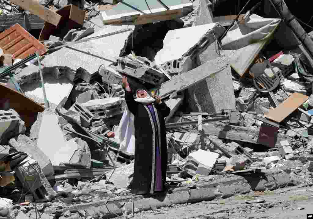A Palestinian woman reacts near the rubble of a building housing&nbsp;The Associated Press, broadcaster Al-Jazeera and other media outlet, in Gaza City. The building was destroyed by an Israeli airstrike on Saturday.