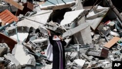 A Palestinian woman reacts near the rubble of a building housing&nbsp;The Associated Press, broadcaster Al-Jazeera and other media outlet, in Gaza City. The building was destroyed by an Israeli airstrike on Saturday.