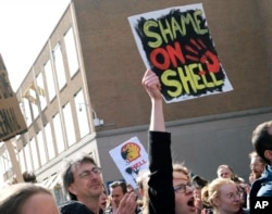 FILE - Climate activists demonstrate outside the Shell headquarters in The Hague, Netherlands, April 5, 2019, prior to deliver a court summons to Shell in a case aimed at forcing the energy giant to do more to rein in carbon emissions.