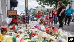 Mourners bring flowers to a makeshift memorial, Aug. 6, 2019, for the slain and injured in the Oregon District after a mass shooting early Sunday in Dayton, Ohio.