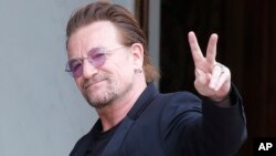 FILE - U2 singer Bono makes a peace sign as he arrives for a meeting at the Elysee Palace, in Paris, France, July 24, 2017.