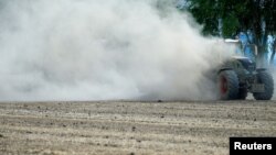 A farmer harrows a dried out field near Geinsheim, Germany, July 30, 2018. 