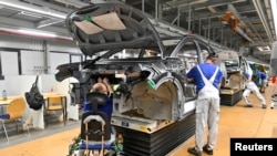 FILE - Technicians work on the assembly line of Volkswagen's electric ID.3 car in Zwickau, Germany, June 23, 2021.