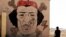 A Libyan man sits near a mural of Moammar Gadhafi in Benghazi, Libya, September 20, 2012.