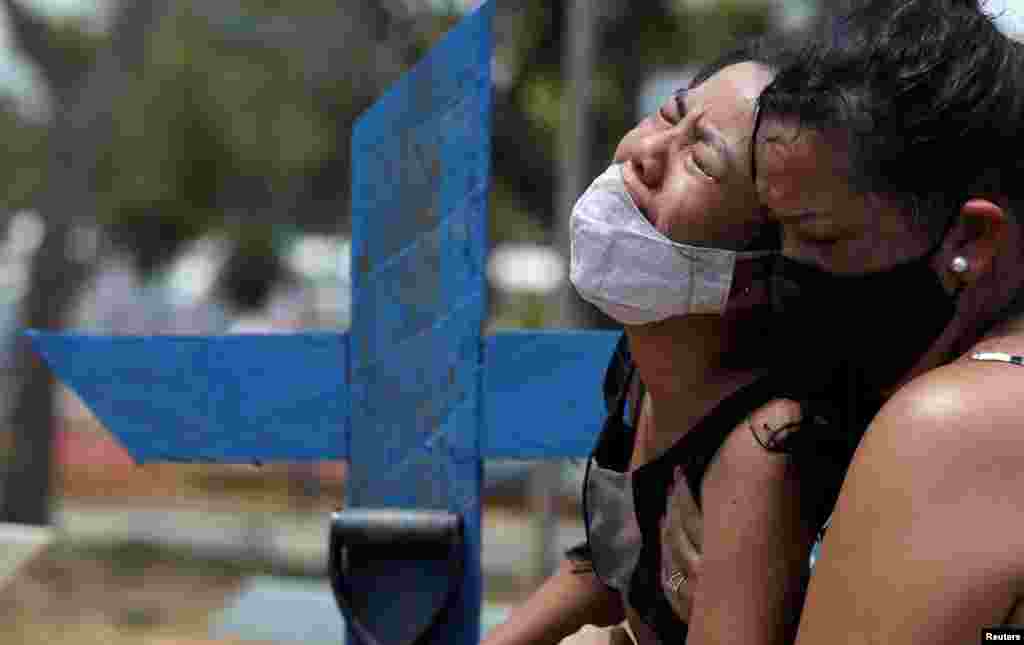 Kelvia Andrea Goncalves is comforted by her aunt Vanderleia dos Reis Brasao, at the Parque Taruma cemetery in Manaus, Brazil, Jan. 17, 2021, during the burial of her mother Andrea dos Reis Brasao, 39, who passed away due to the COVID-19.