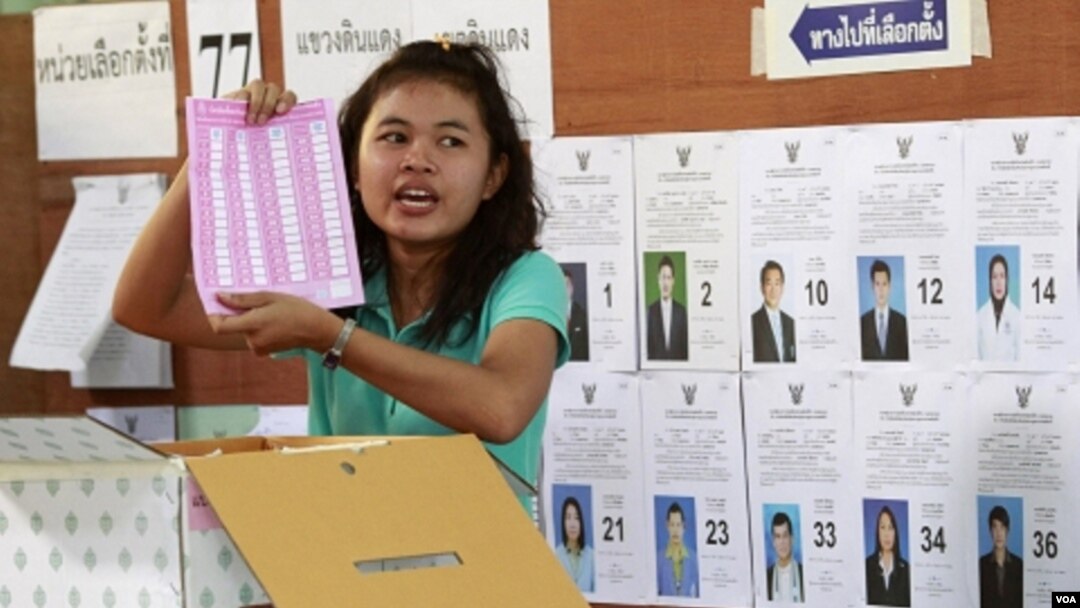 Pekerja pemilu di sebuah TPS di Bangkok menunjukkan kartu suara saat perhitungan pemilu Thailand (7/3).