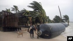 Un hombre inspecciona unos amortiguadores arrancandos de algún muelle por los vientos y la marea, cerca de Chetumal, México, provocados por Ernesto.