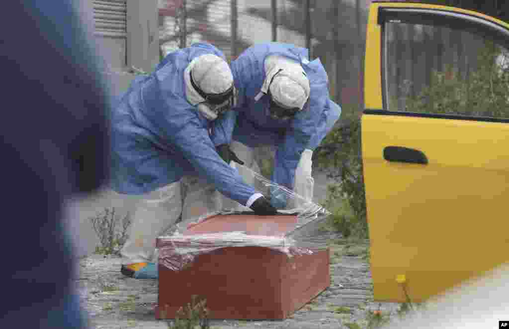 Funeral workers wrap a coffin containing the body of a man who died inside a taxi as he was being taken to hospital by relatives, with plastic, in Quito, Ecuador, July 15, 2020. According to Police Captain Manuel Pazmiño the man died inside the taxi of suspected new coronavirus symptoms.