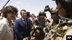 French President Emmanuel Macron, center, and Defense Minister Sylvie Goulard meet soldiers of Operation Barkhane, France's largest overseas military operation, in Gao, northern Mali, May 19, 2017.