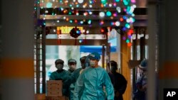 Petugas kesehatan dengan alat pelindung berjalan di area penguncian di Kwai Chung Estate, di Hong Kong, Sabtu, 22 Januari 2022. (Foto: AP/Kin Cheung)