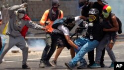 Manifestantes ayudan a un periodista golpeado por una bomba lacrimógena en las manifestaciones del lunes en Caracas.