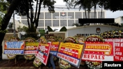 
Seorang pekerja mengatur karangan bunga dan papan ucapan selamat dari orang-orang setelah pemilihan minggu ini di luar kantor Komisi Pemilihan Umum (KPU) di Jakarta, 21 April 2019. (Foto: Reuters)