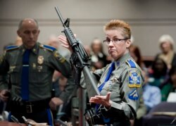 FILE - A firearms training unit detective holds up a Bushmaster AR-15 rifle, the same make and model of gun used in the Sandy Hook school shooting, during a hearing on gun laws in Hartford, Conn., Jan. 28, 2013.