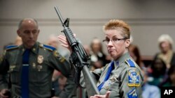 FILE - A firearms training unit detective holds up a Bushmaster AR-15 rifle, the same make and model of gun used in the Sandy Hook school shooting, during a hearing on gun laws in Hartford, Conn., Jan. 28, 2013.